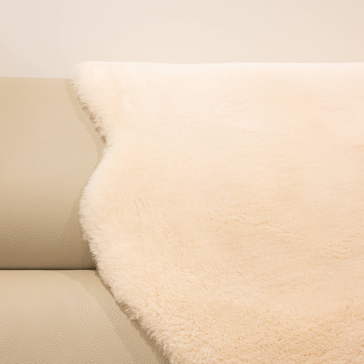 Dusk sheepskin baby rug draped over seating showing dense wool texture and warm neutral tone