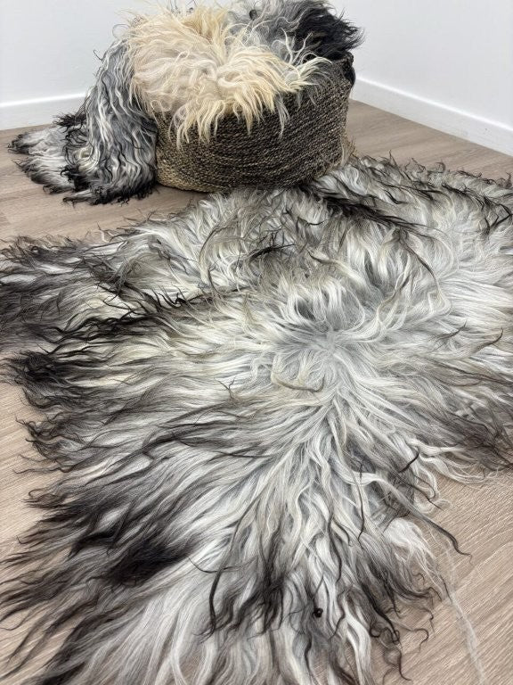 Greenlandic sheepskin rug with long crinkled wool draped over a woven chair and styled on a timber floor in a modern interior