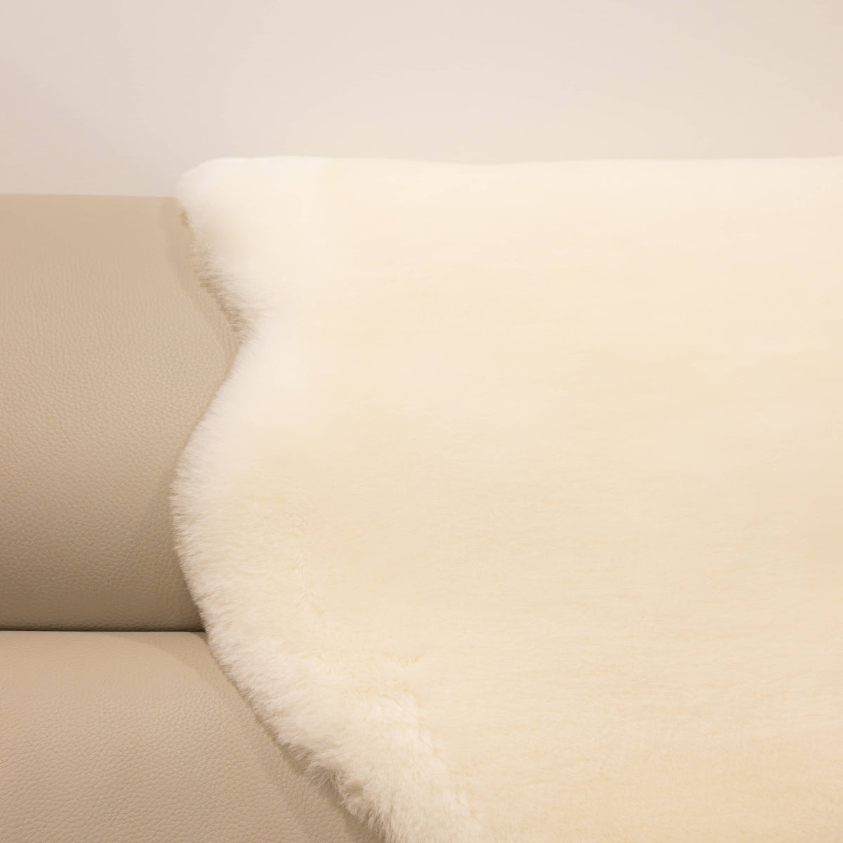 Natural white sheepskin baby rug draped over seating showing dense wool texture and clean neutral tone