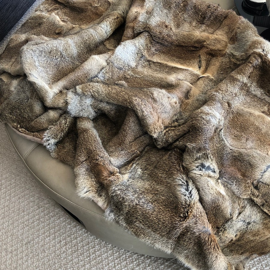 Brown rabbit hide blanket draped over a chair showing soft natural texture