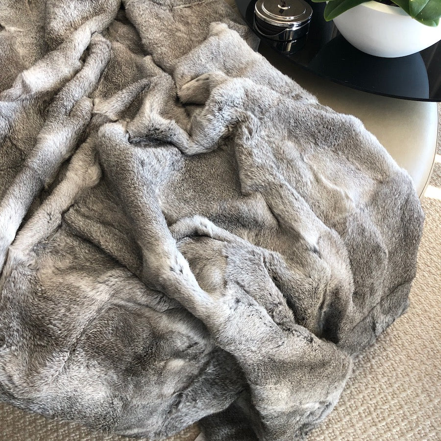Grey rabbit hide blanket draped over a chair showing natural soft hair texture