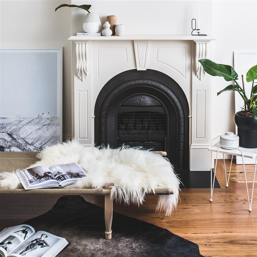 Icelandic sheepskin rug in natural white styled over a bench in a living room with a fireplace