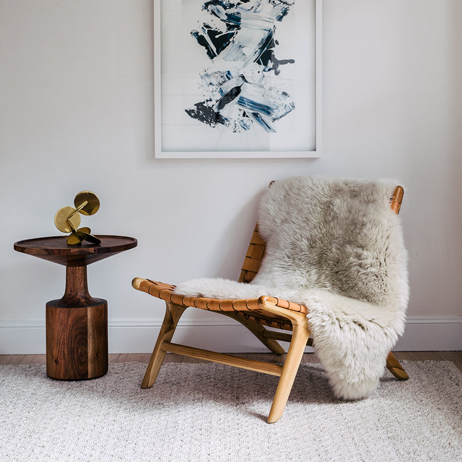 Linen Australian merino sheepskin rug styled over a timber lounge chair in a neutral interior