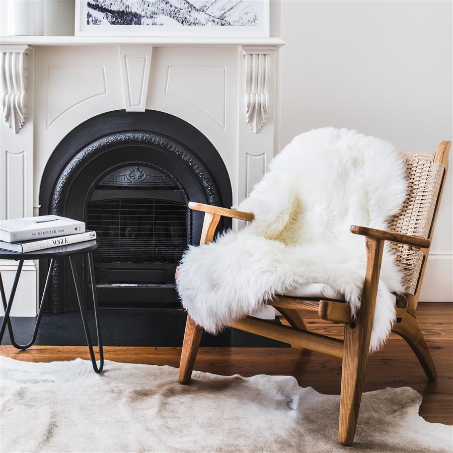 Natural white Merino sheepskin rug styled over armchair in living room