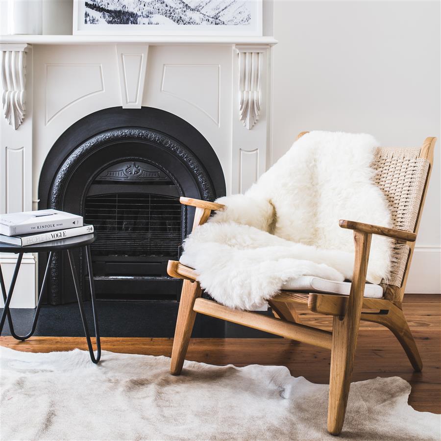 Icelandic shorn sheepskin rug in natural white styled over an armchair in a living room setting