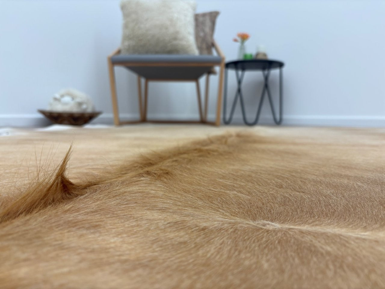 Close-up detail of a beige and white cowhide rug showing smooth natural hair texture and colour variation