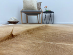 Close-up detail of a beige and white cowhide rug showing smooth natural hair texture and colour variation
