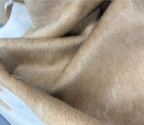 Close-up of a premium beige and white cowhide rug highlighting the soft natural hair-on-hide texture and smooth leather finish.