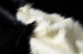 Close-up detail of a black and white cowhide rug showing smooth natural hair texture and strong colour contrast