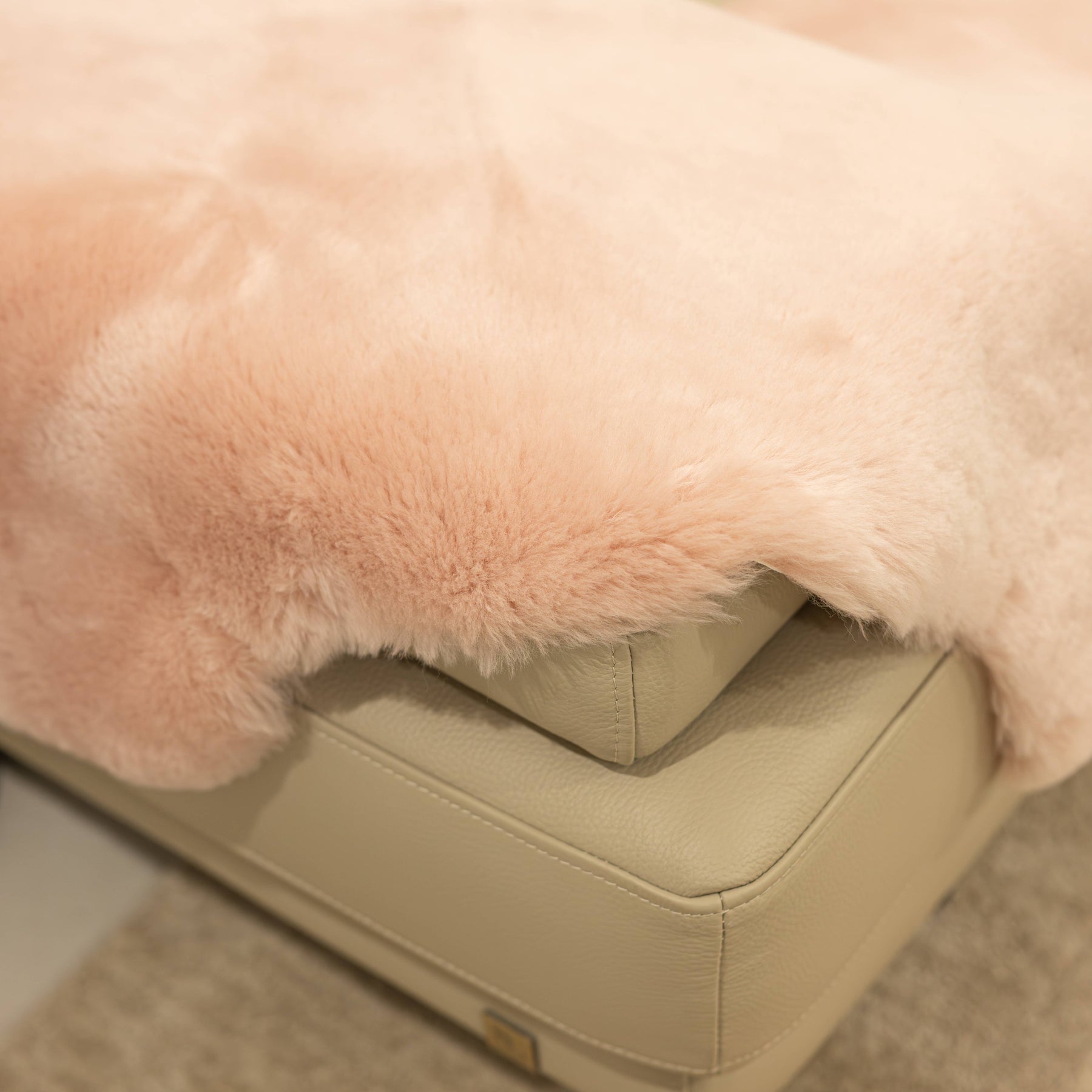 Close-up of blush sheepskin baby rug showing dense wool pile and softly finished edge