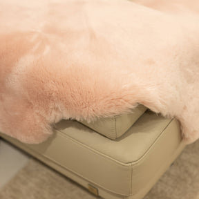 Close-up of blush sheepskin baby rug showing dense wool pile and softly finished edge
