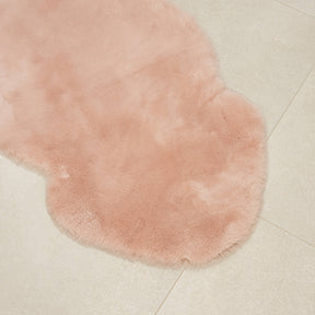 Blush sheepskin baby rug laid flat showing natural shape and dense wool texture