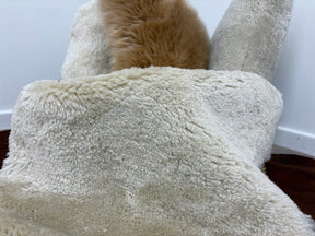Detail view of bone shearling rug showing short, tightly curled wool texture across the surface