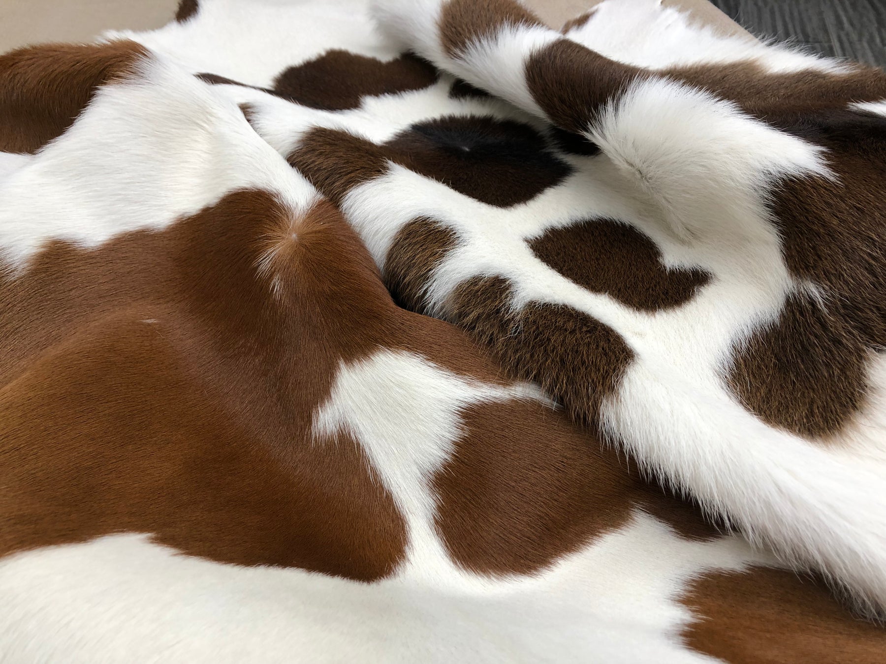Close-up detail of a brown and white calf hide rug showing fine smooth hair and natural pattern variation