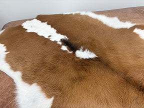 Natural brown and white calf hide rug showing soft texture and natural markings