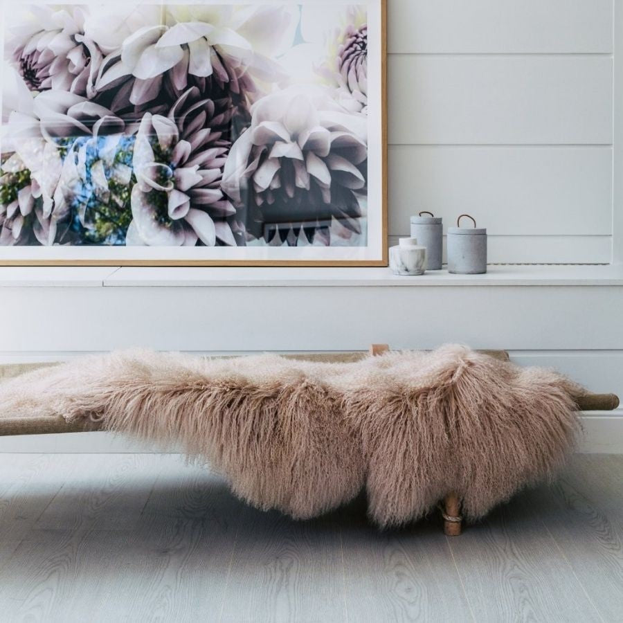 Camel Mongolian sheepskin area rug crafted from four hides with long, silky fleece, styled over a bench in a warm interior setting