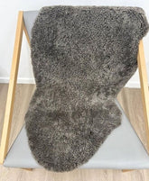 Chocolate fleck shearling sheepskin rug styled over a chair with soft, tightly curled wool and a luxurious texture.