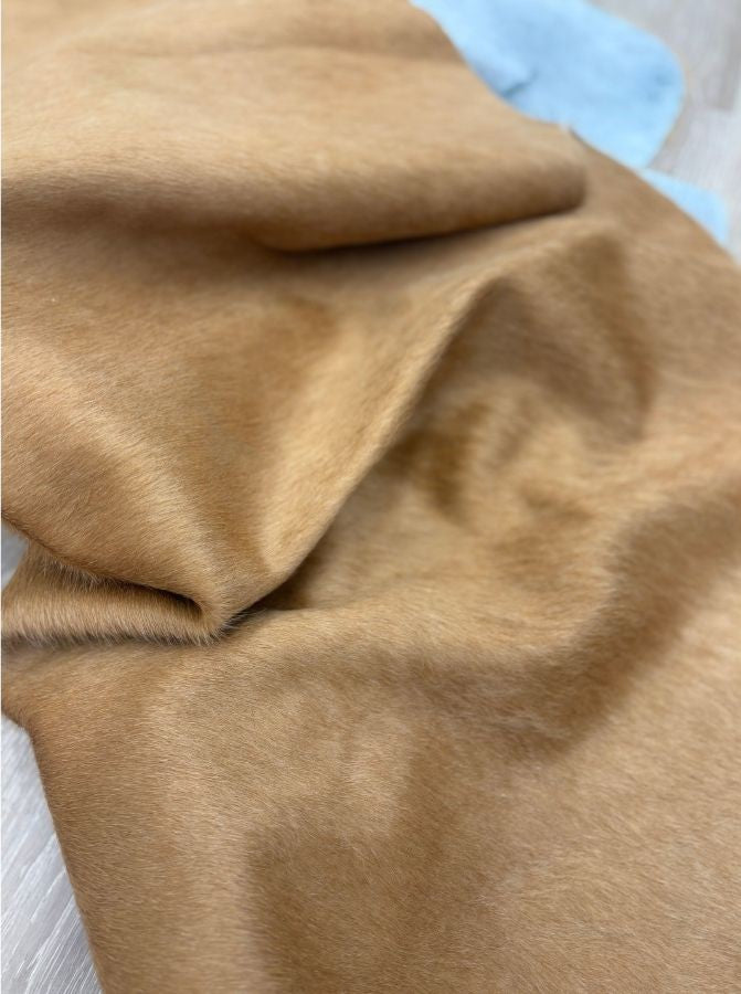 Close-up of beige cowhide rug showing soft natural leather texture and honey tones