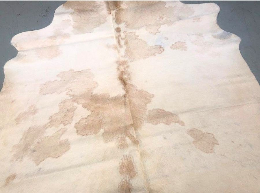 Close-up detail of beige and white cowhide rug showing natural markings and hair texture