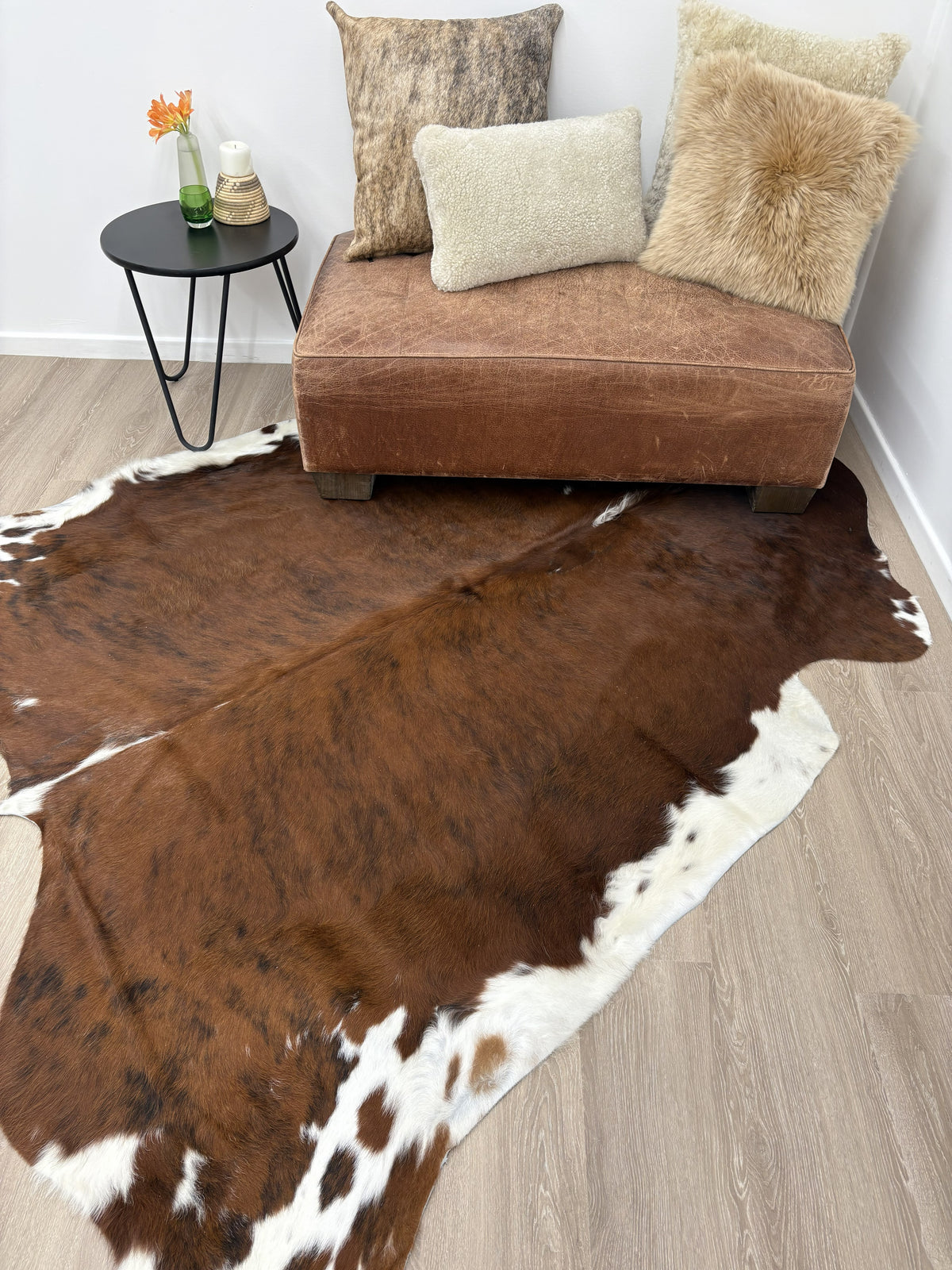 Exotic brindle cowhide rug styled on a wooden floor beside a sofa