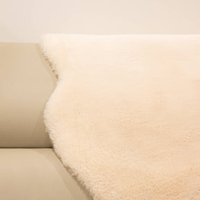 Dusk sheepskin baby rug draped over seating showing dense wool texture and warm neutral tone