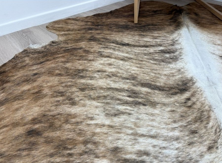 Close-up detail of a large exotic brindle cowhide rug showing natural brown and tan markings and hair-on hide texture