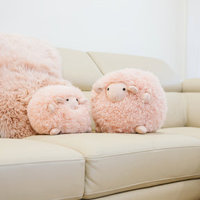 Two blush sheepskin toys made from natural sheepskin styled on a sofa
