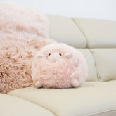 Geraldine sheepskin toy made from natural blush sheepskin styled on a sofa