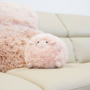 Geraldine sheepskin toy made from natural blush sheepskin styled on a sofa
