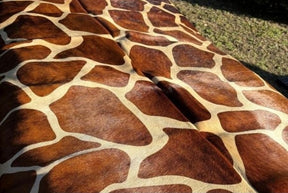 Close-up detail of giraffe print cowhide rug showing brown and cream dyed pattern on natural hide