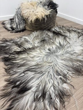 Greenlandic sheepskin rug with long crinkled wool draped over a woven chair and styled on a timber floor in a modern interior