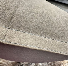 Close up of grey nubuck leather cushion showing natural grain texture and stitched edge detail