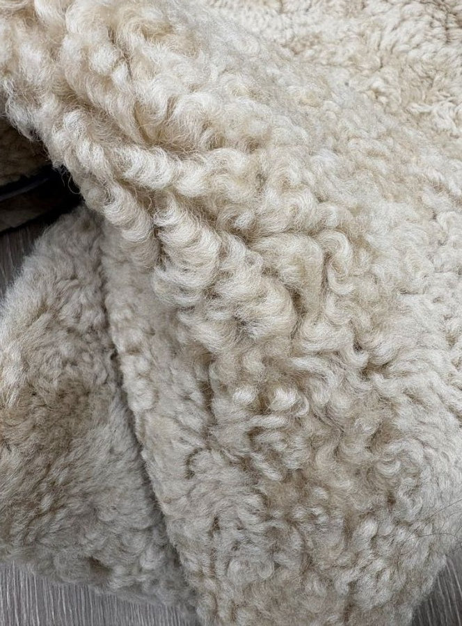 Detailed view of genuine honey shearling with dense curly wool and warm honey-toned fibres.