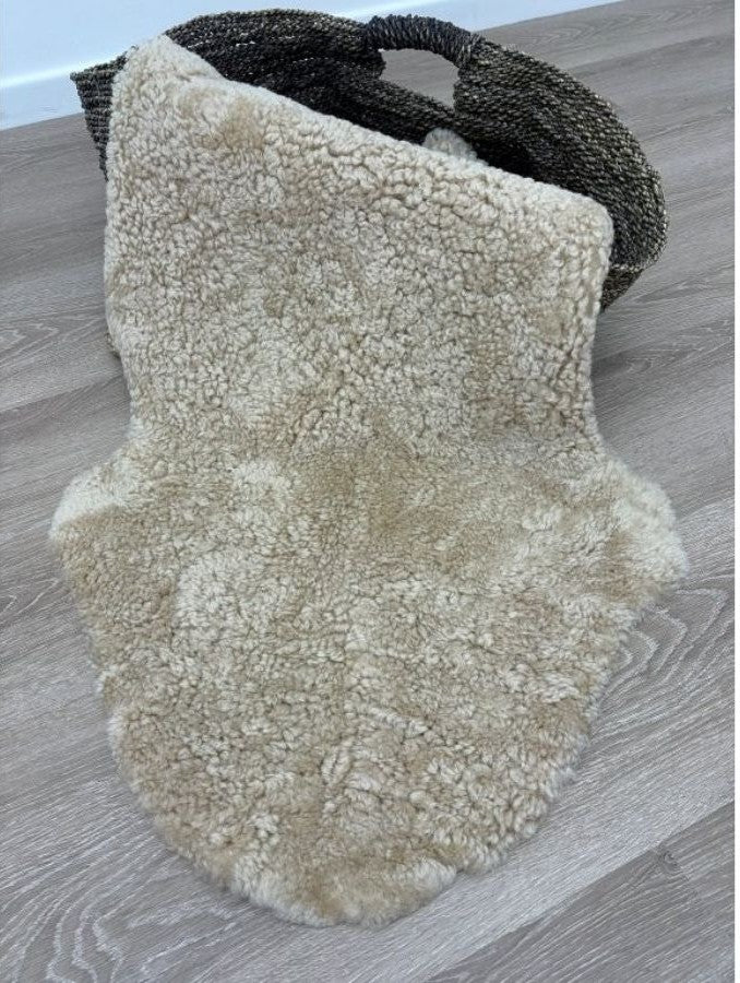 Honey shearling sheepskin rug showcasing its natural hide shape and dense curly wool texture.