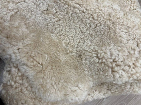 Detailed view of genuine honey shearling with dense, tightly curled wool and warm honey tones.