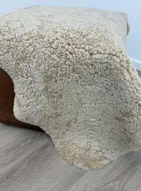 Honey shearling sheepskin rug draped over furniture with soft curled wool and a natural texture.