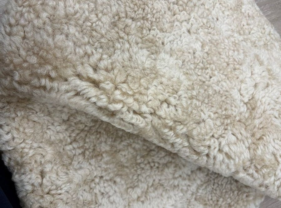 Detailed view of genuine honey shearling with soft curly wool and a luxurious textured finish.