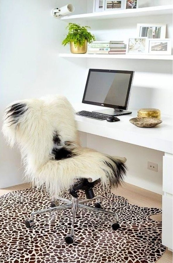 Icelandic sheepskin rug in white with black spots styled over a chair in a home workspace