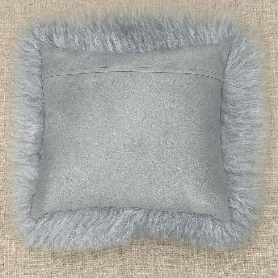 Light grey Mongolian sheepskin cushion photographed flat, showing long hair trim and cotton velour backing on a neutral background
