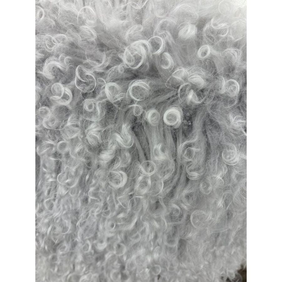 Close-up detail of light grey Mongolian sheepskin cushion showing soft, curly long hair texture