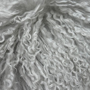 Close-up of light grey Mongolian sheepskin lumbar cushion showing long, naturally curly hair texture