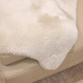 Linen sheepskin baby rug draped over seating showing soft wool texture and natural variation