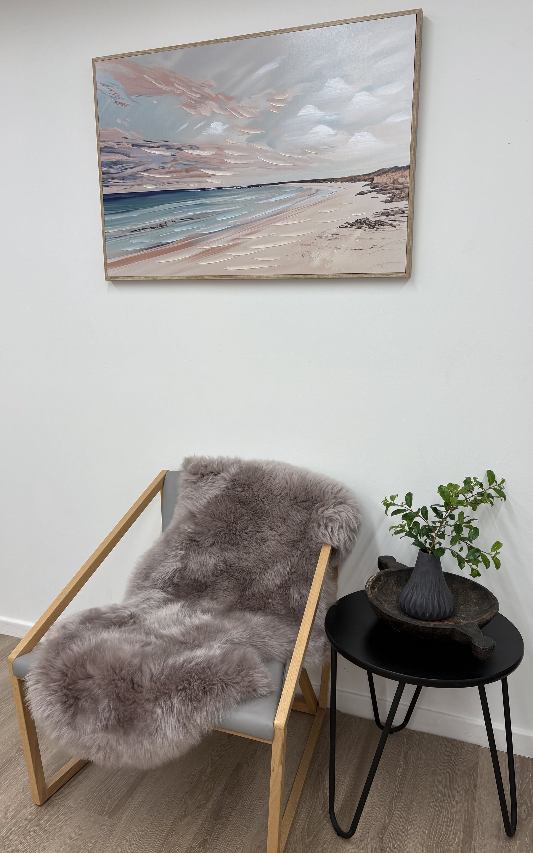 Merino sheepskin rug in mushroom tone draped over a chair in a neutral interior