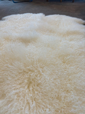 Close-up detail of the soft, dense fleece on a natural white Mongolian sheepskin area rug