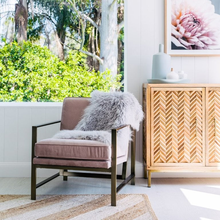 Light grey Mongolian sheepskin rug styled over an armchair in a bright living space