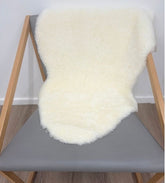 Natural white shearling sheepskin rug styled over a chair with dense wool and a soft, luxurious finish.