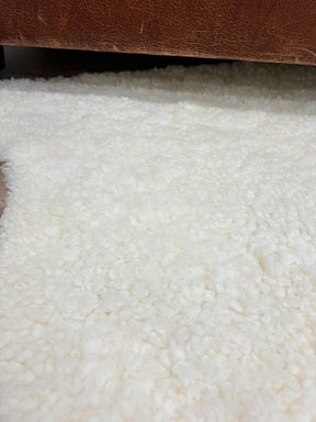 Close-up of natural white shearling rug showing short, tightly curled wool surface