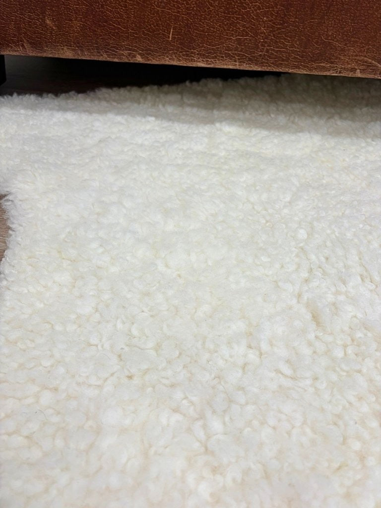 Close-up of natural white shearling rug showing short, tightly curled wool surface