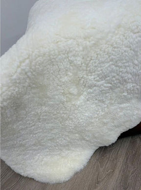 Natural white shearling sheepskin rug styled over furniture with dense wool and a soft, plush finish.