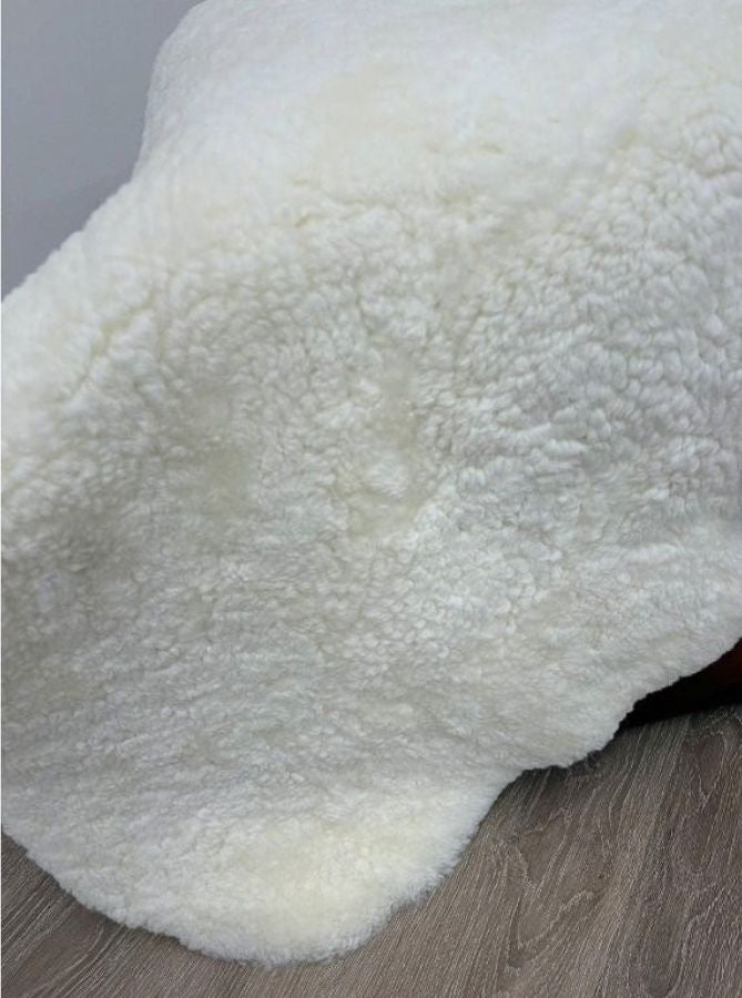 Natural white shearling sheepskin rug styled over furniture with dense wool and a soft, plush finish.